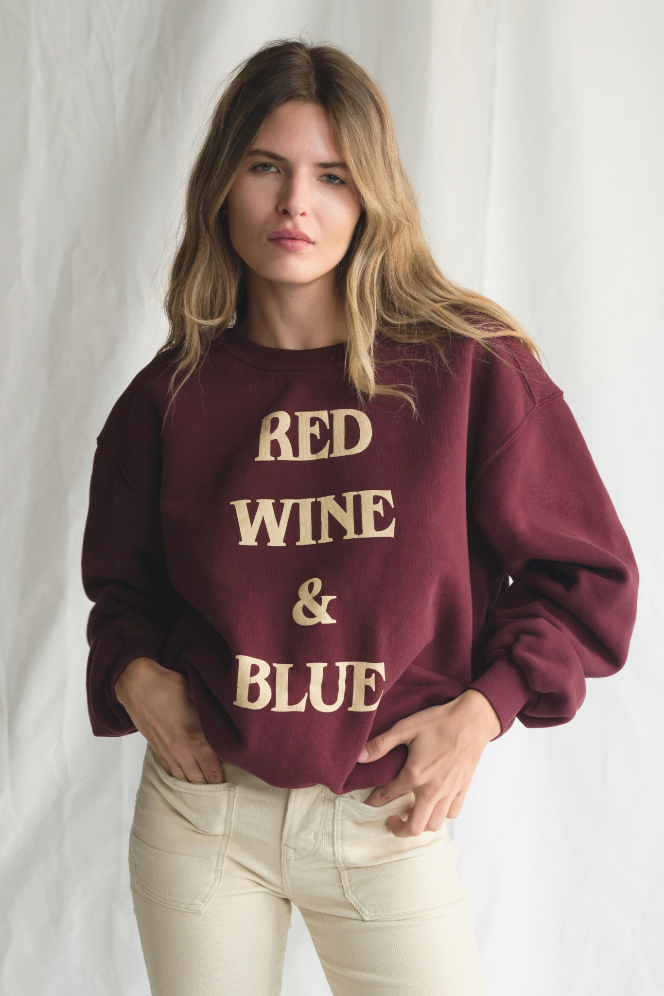 Woman wearing a maroon sweatshirt with 'Red Wine & Blue' text against a white background