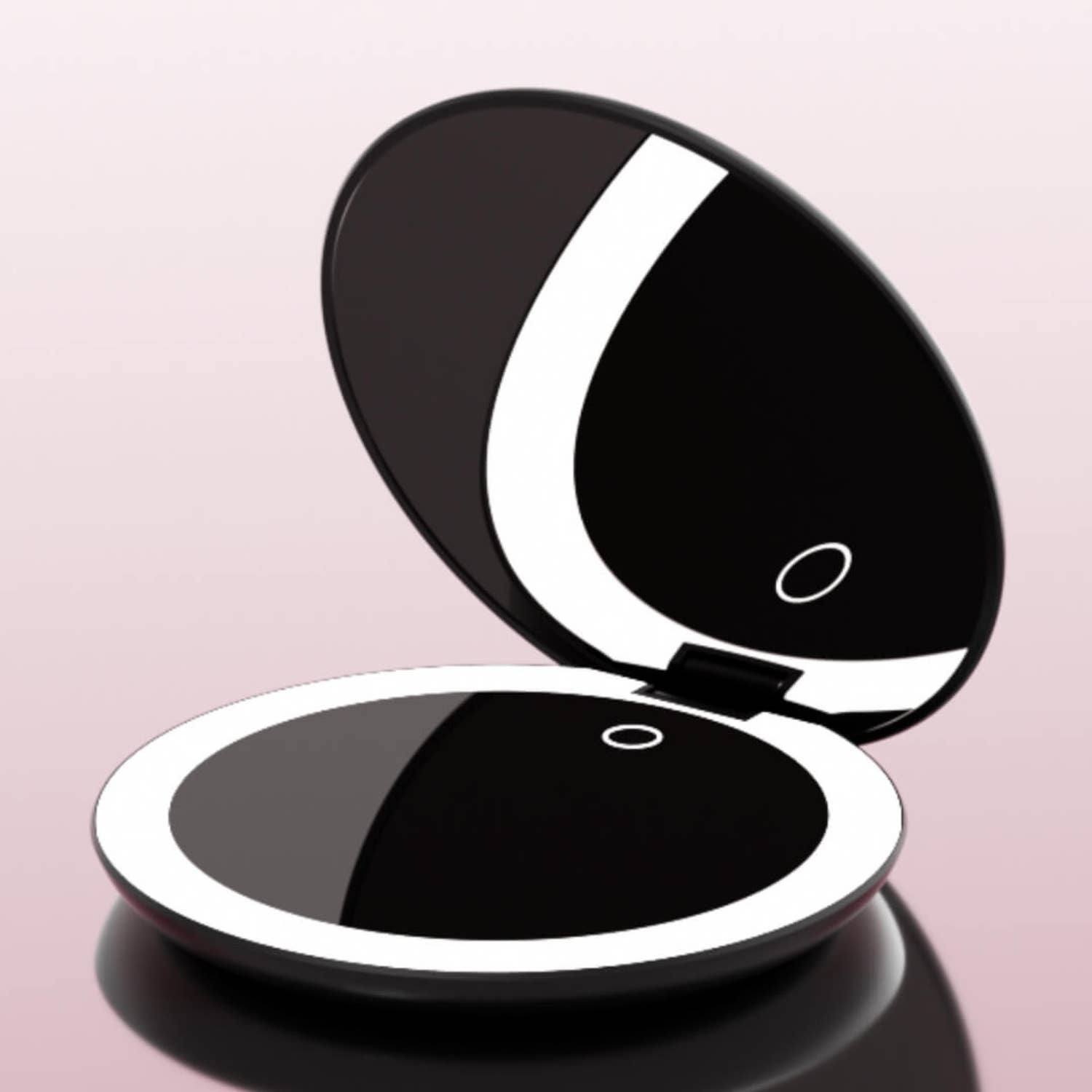 Black compact mirror with a reflective surface on a pink background
