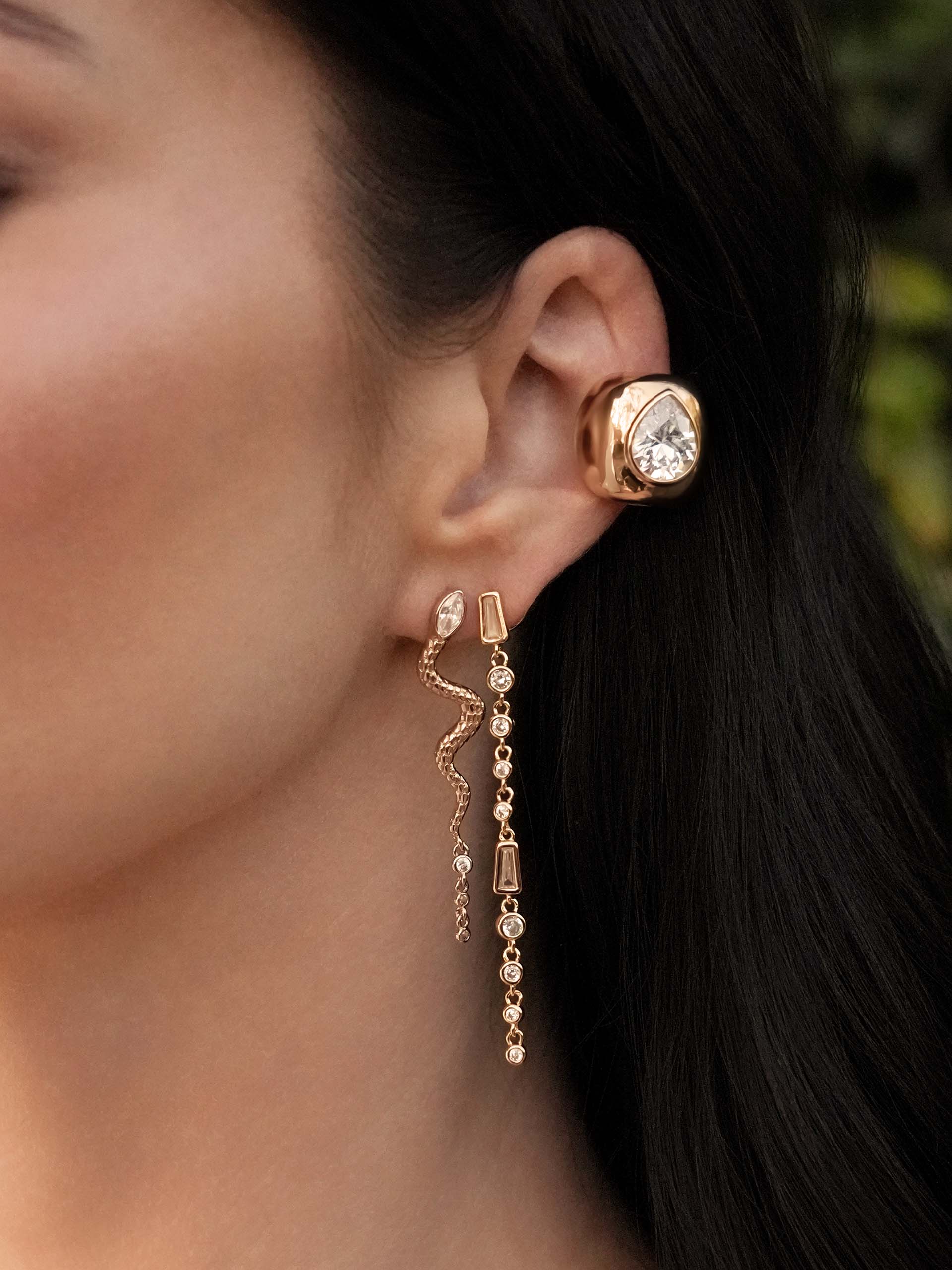 Close-up of a person wearing gold earrings with a blurred background