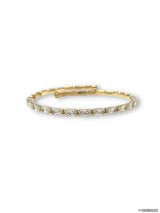 A delicate gold tennis bracelet with small clear stones, photographed on a plain white background.