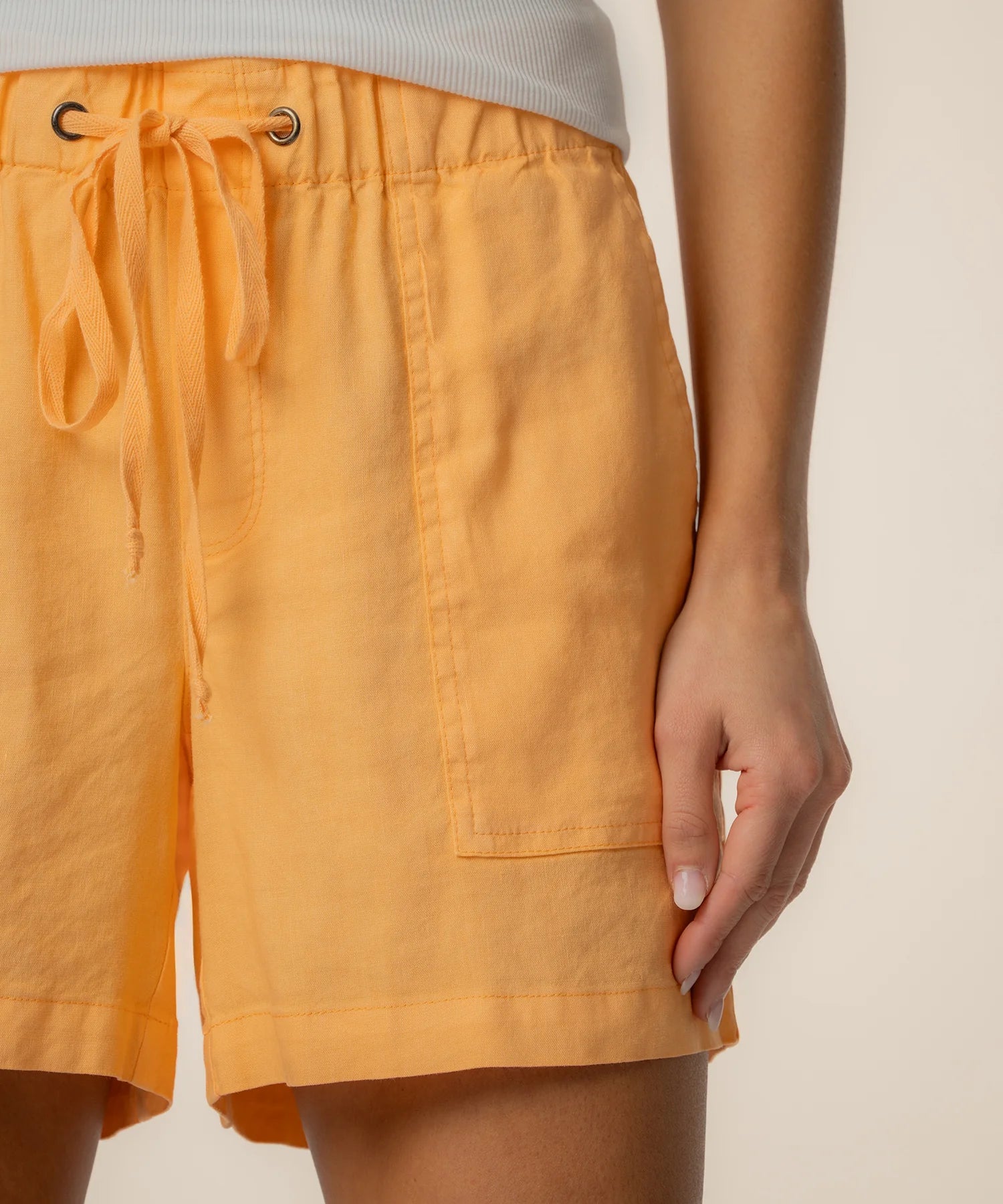 Orange shorts worn by a person on a beige background