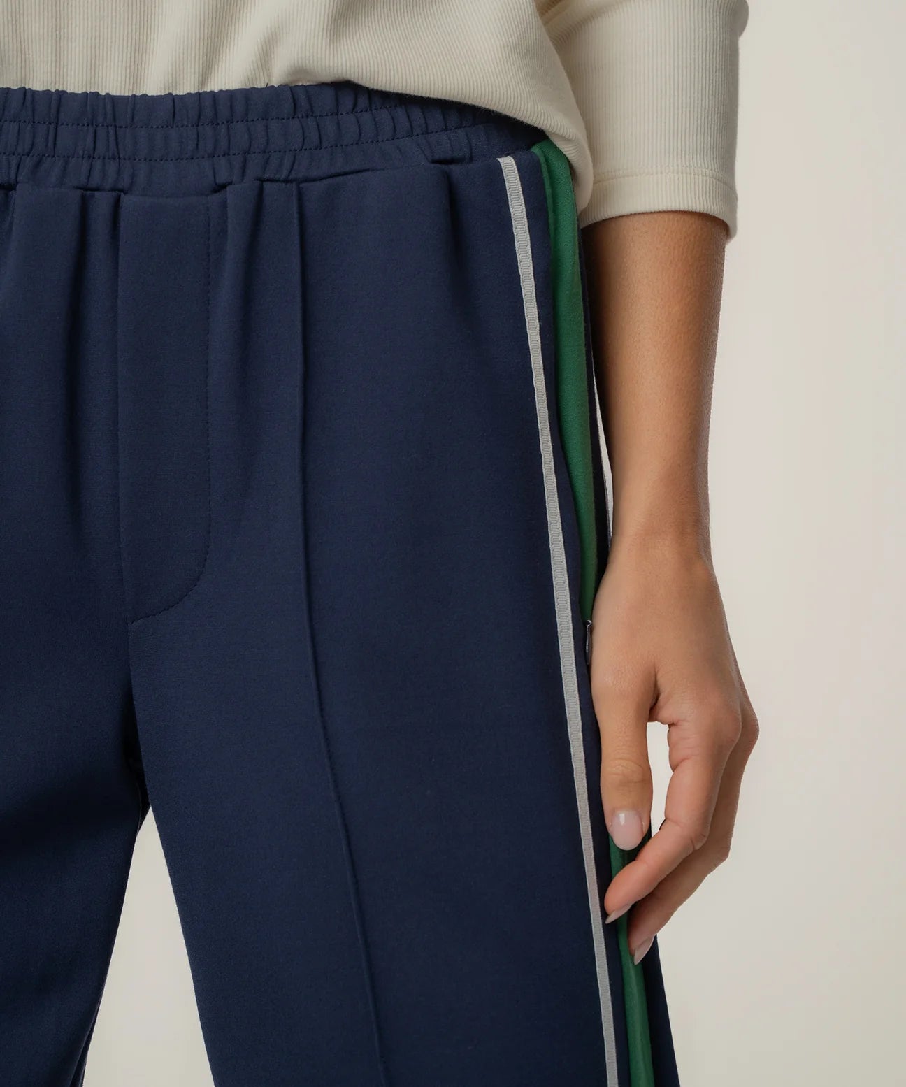 Navy blue pants with colorful side stripes worn by a person on a neutral background