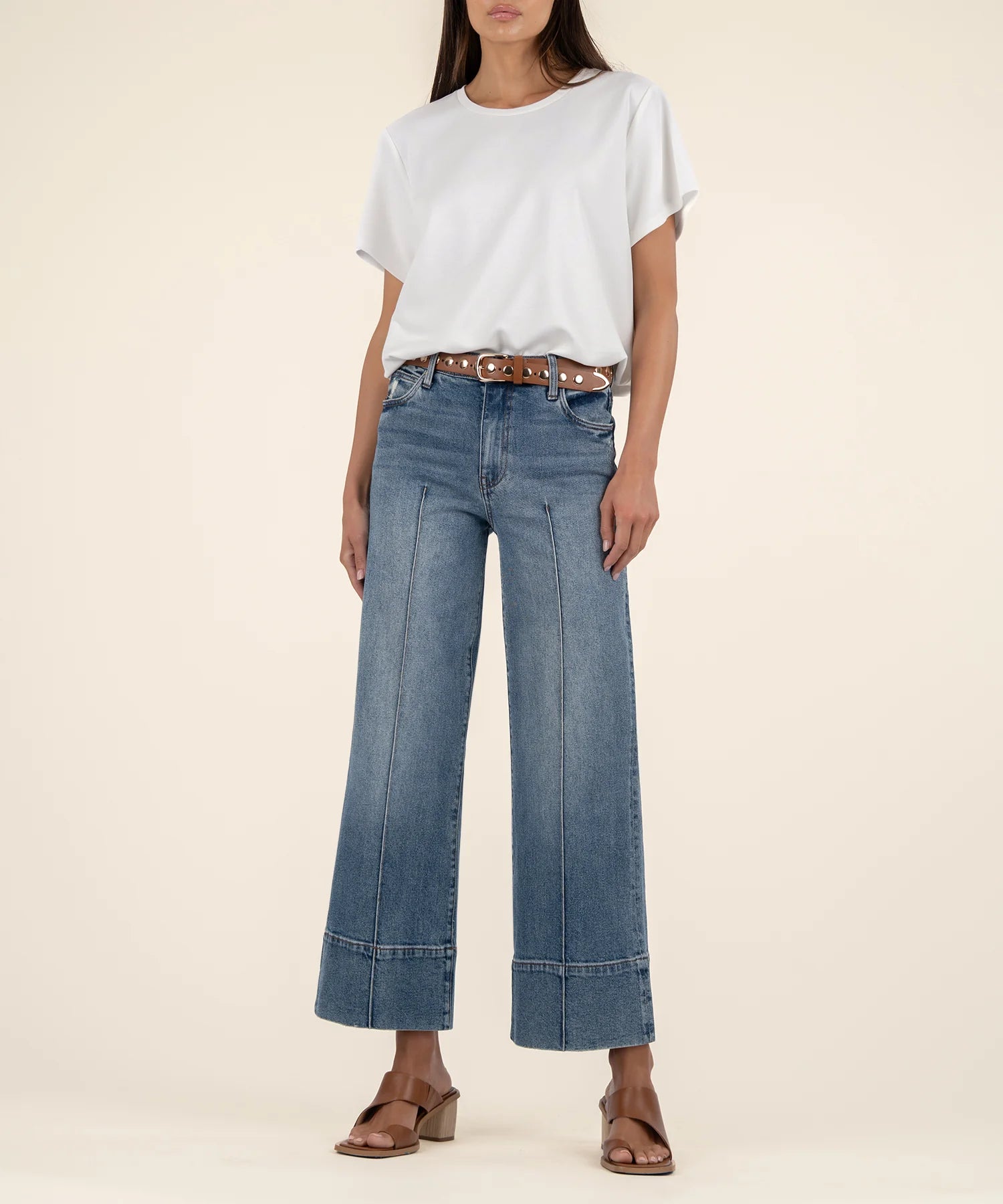 Person wearing a white t-shirt and blue jeans on a beige background