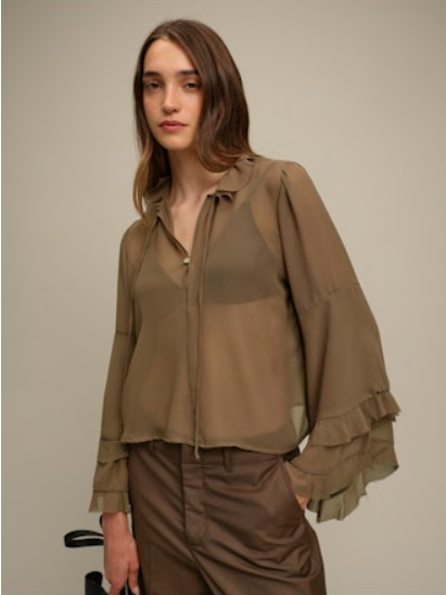 Woman wearing a brown blouse with layered sleeves against a plain background