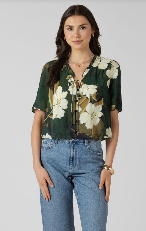 Woman wearing a floral blouse and jeans on a plain background