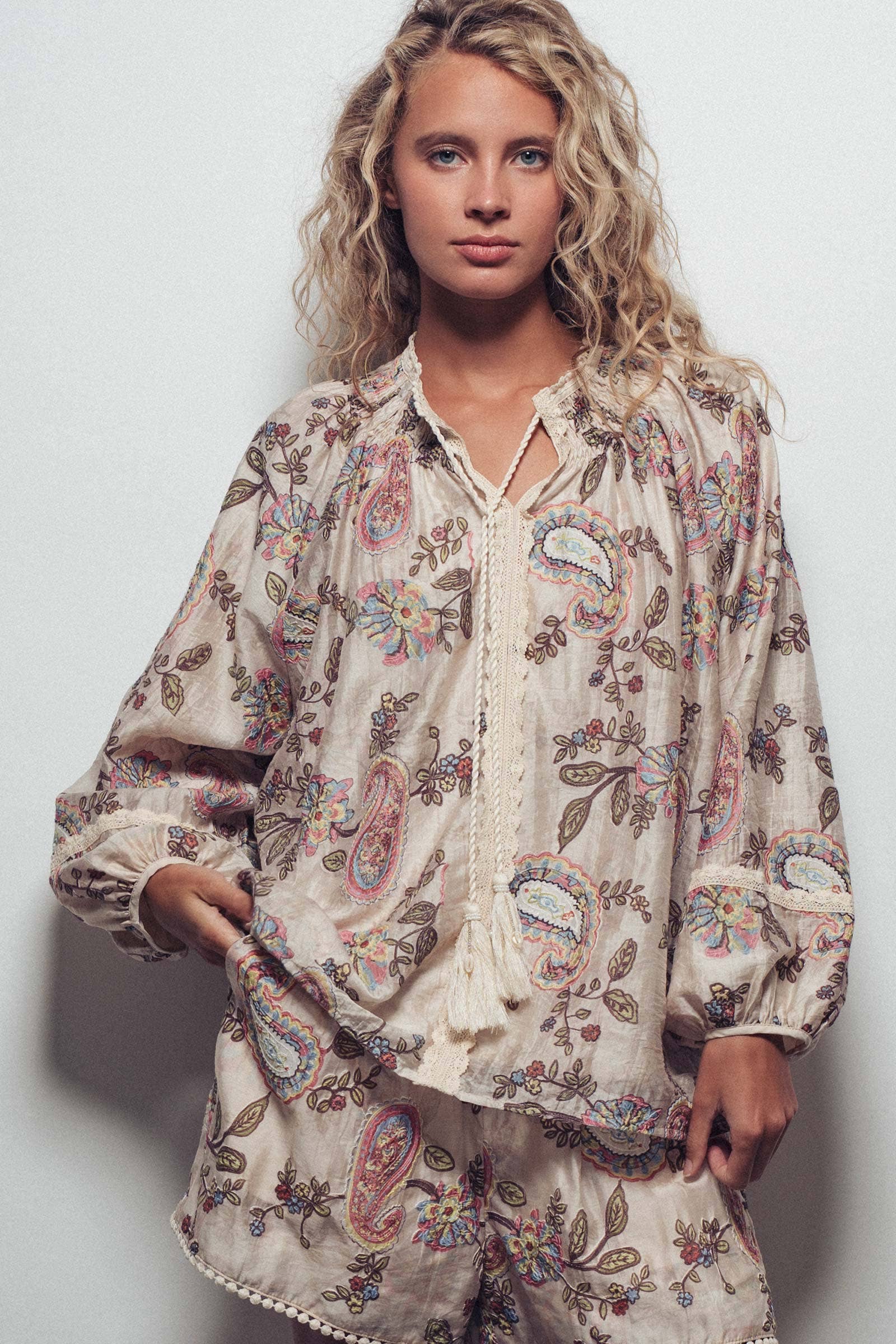 Woman wearing a floral patterned outfit against a plain background