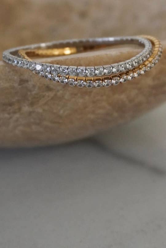 Two gold and silver bracelets on a textured surface