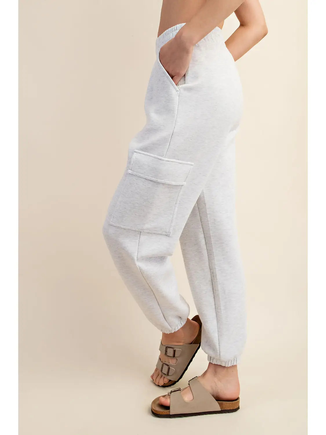 Person wearing light gray cargo pants on a beige background
