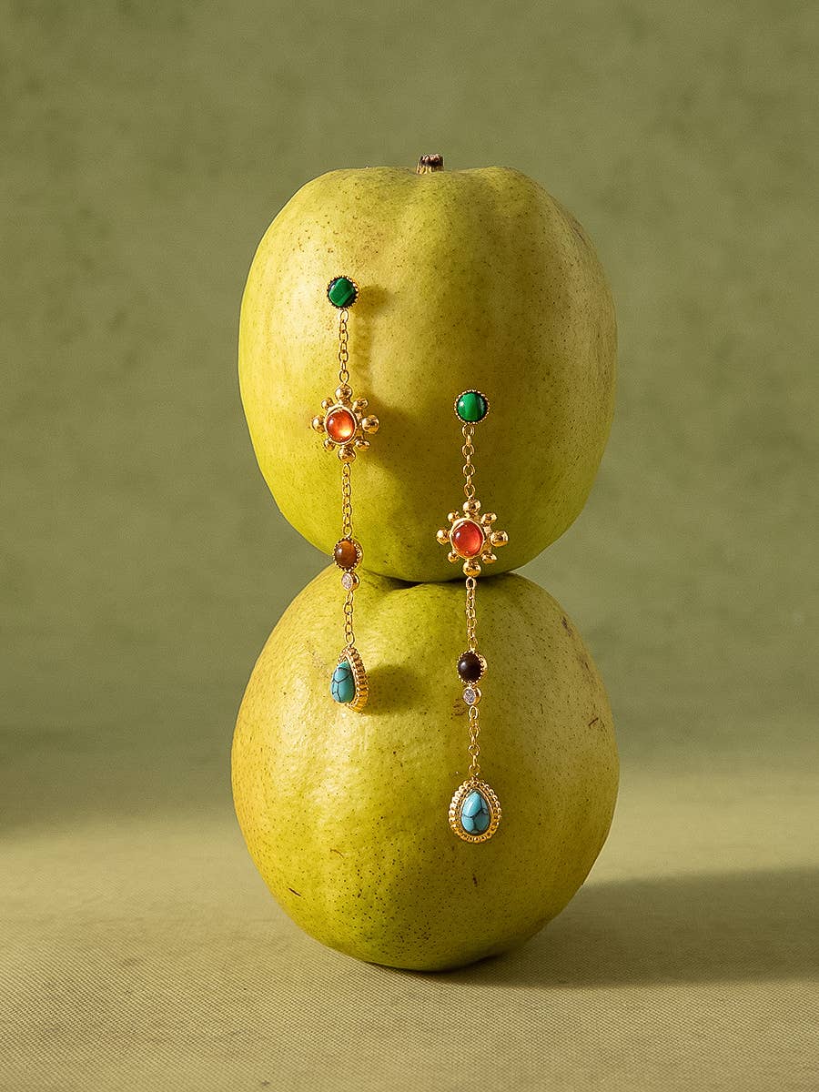 Pair of earrings on two green apples against a green background