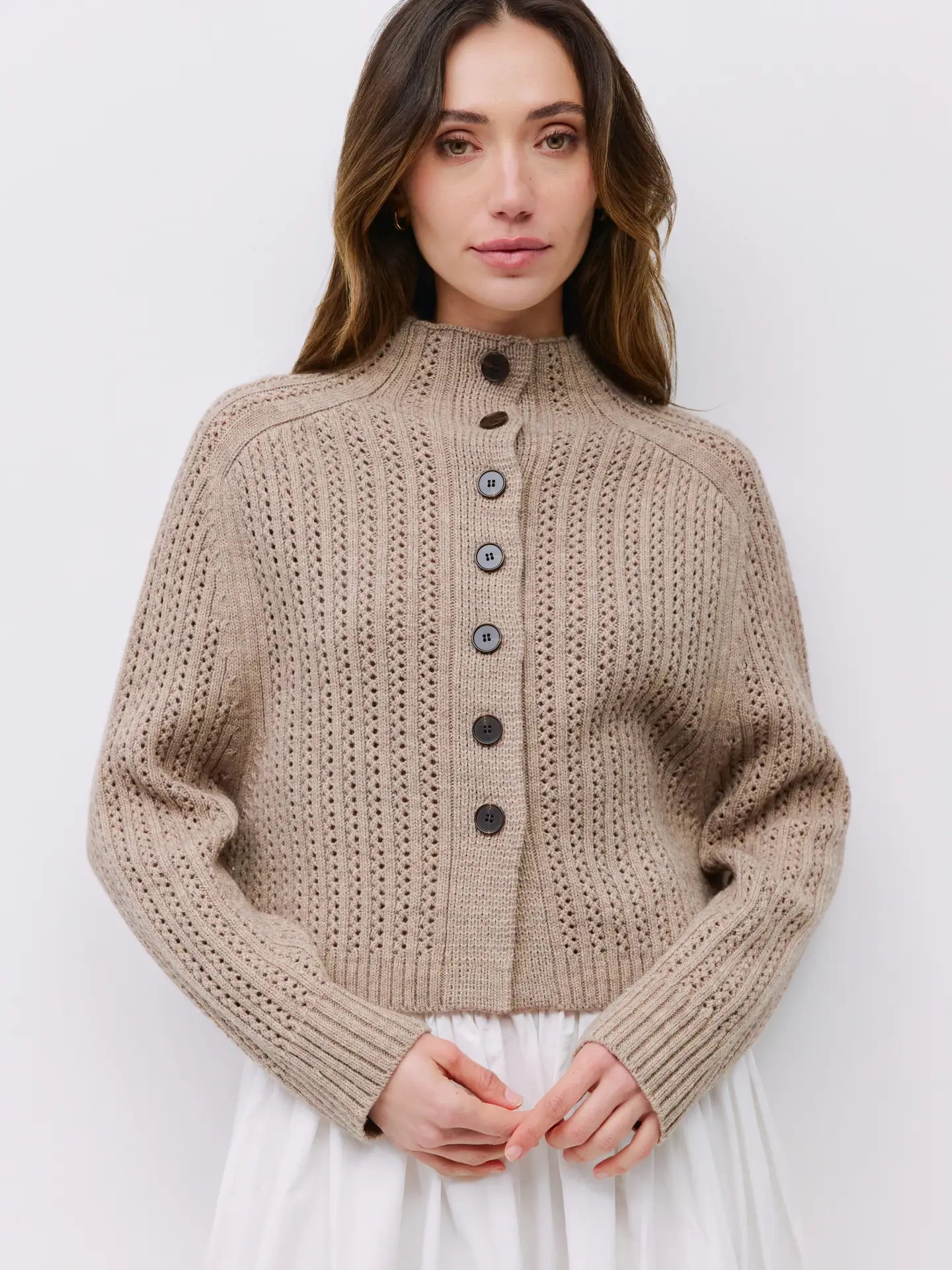 Woman wearing a beige knitted cardigan against a white background