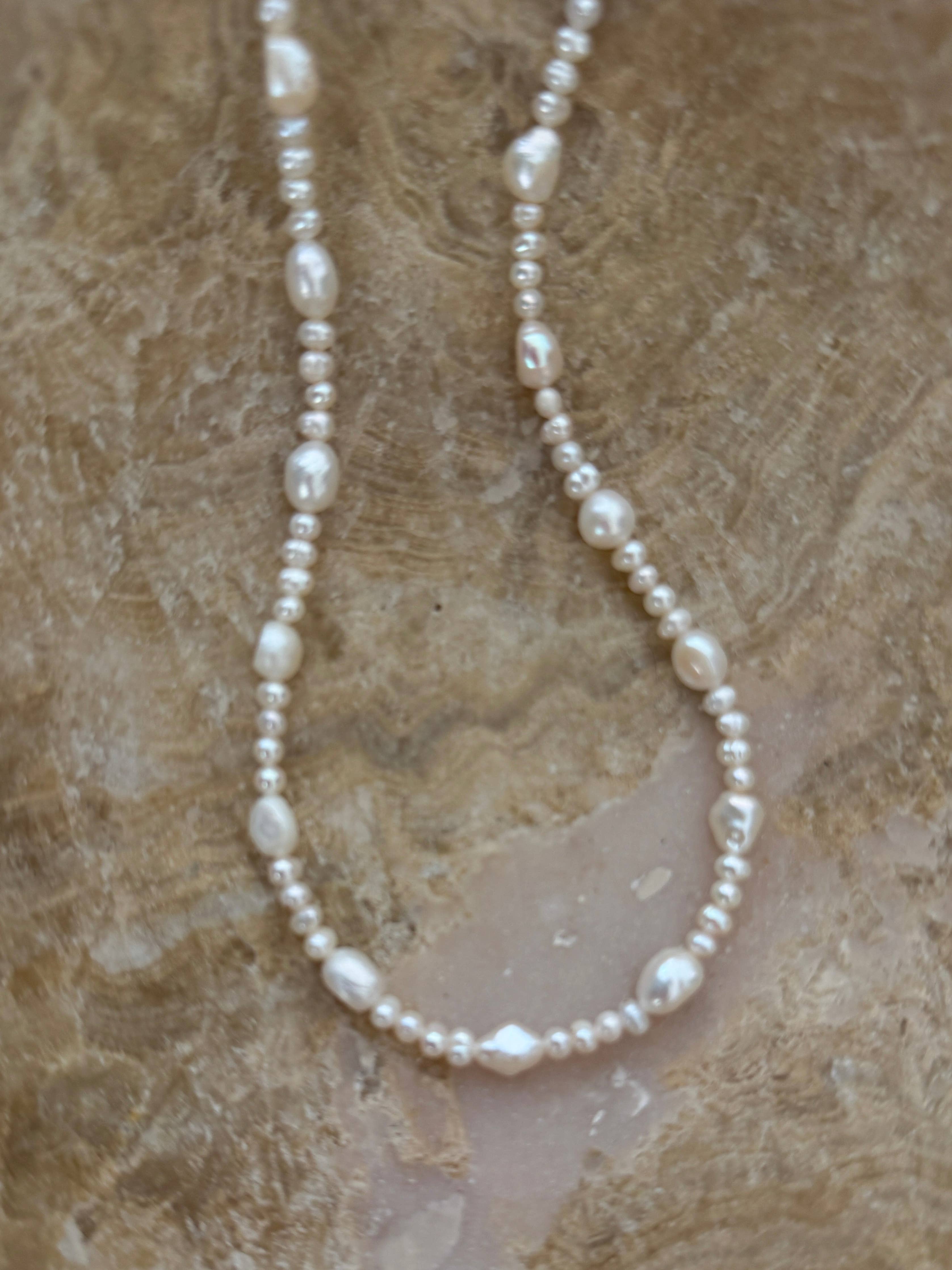Pearl necklace on a textured beige surface
