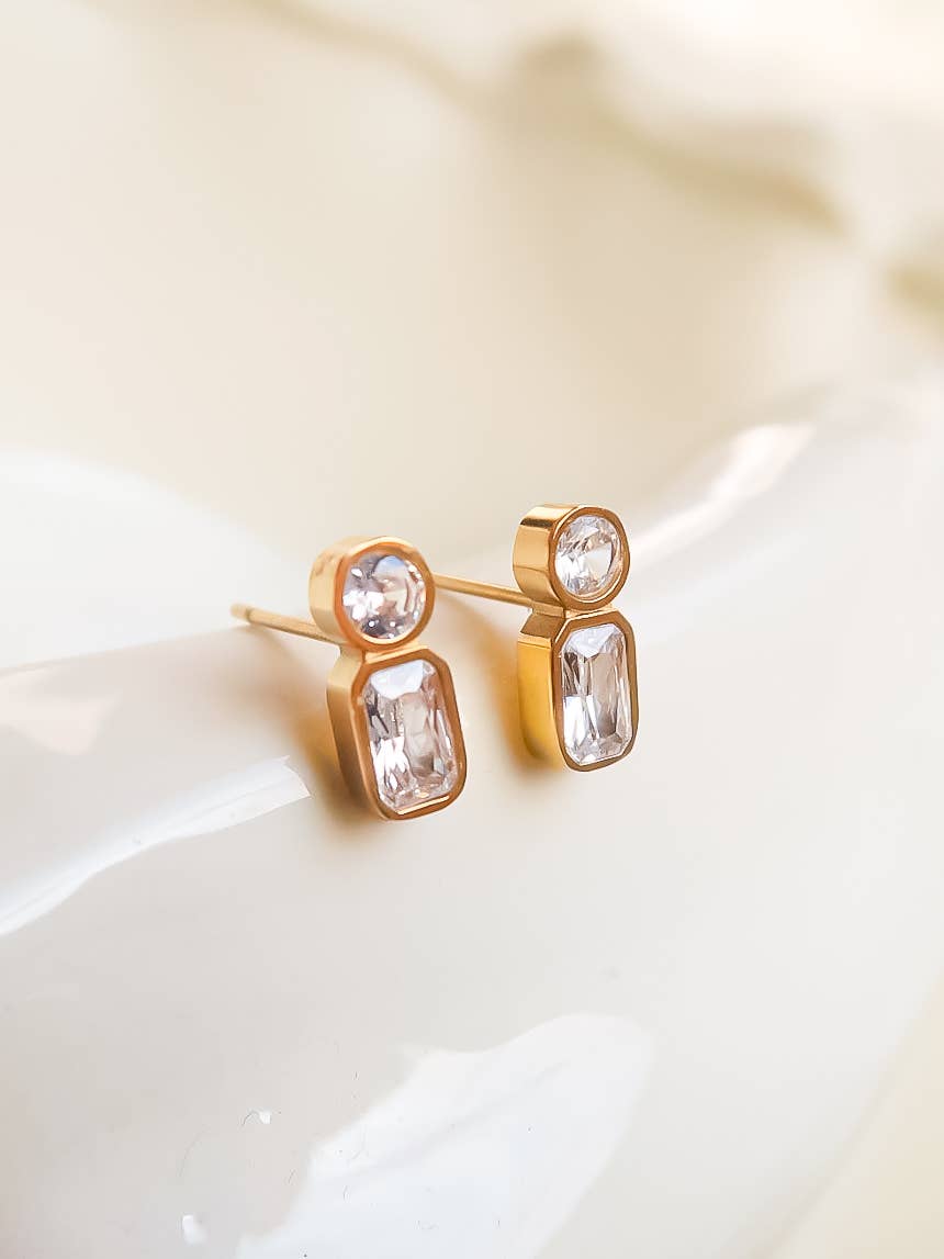Gold earrings with clear gemstones on a white surface