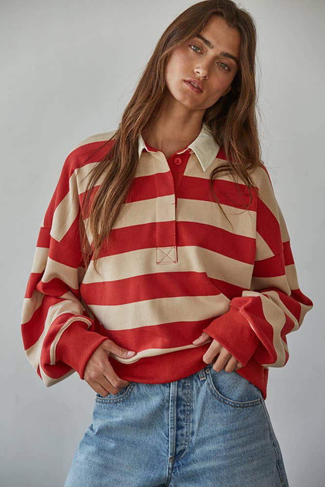 Woman wearing a red and beige striped shirt with blue jeans against a plain background