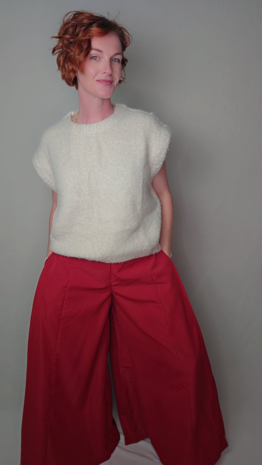Person wearing a white sweater and red skirt against a plain background
