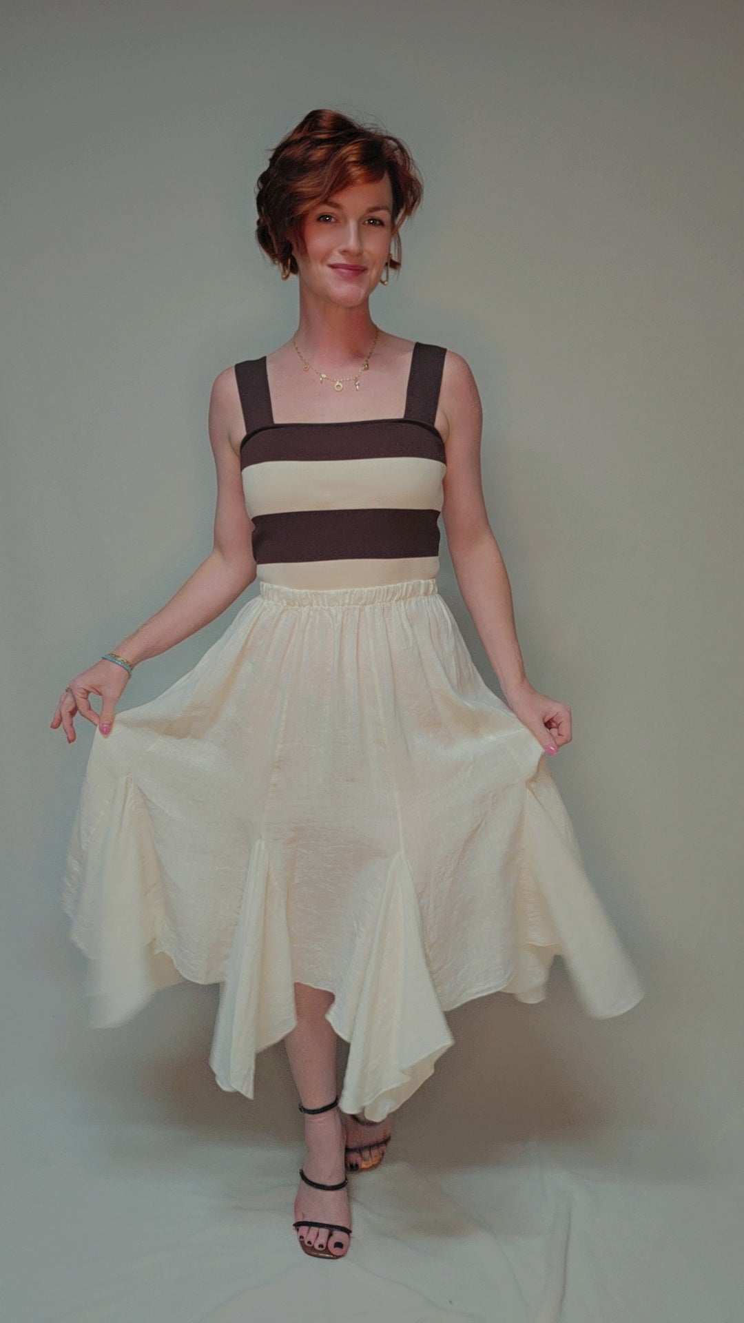 Woman wearing a dress with a brown and beige color scheme on a plain background
