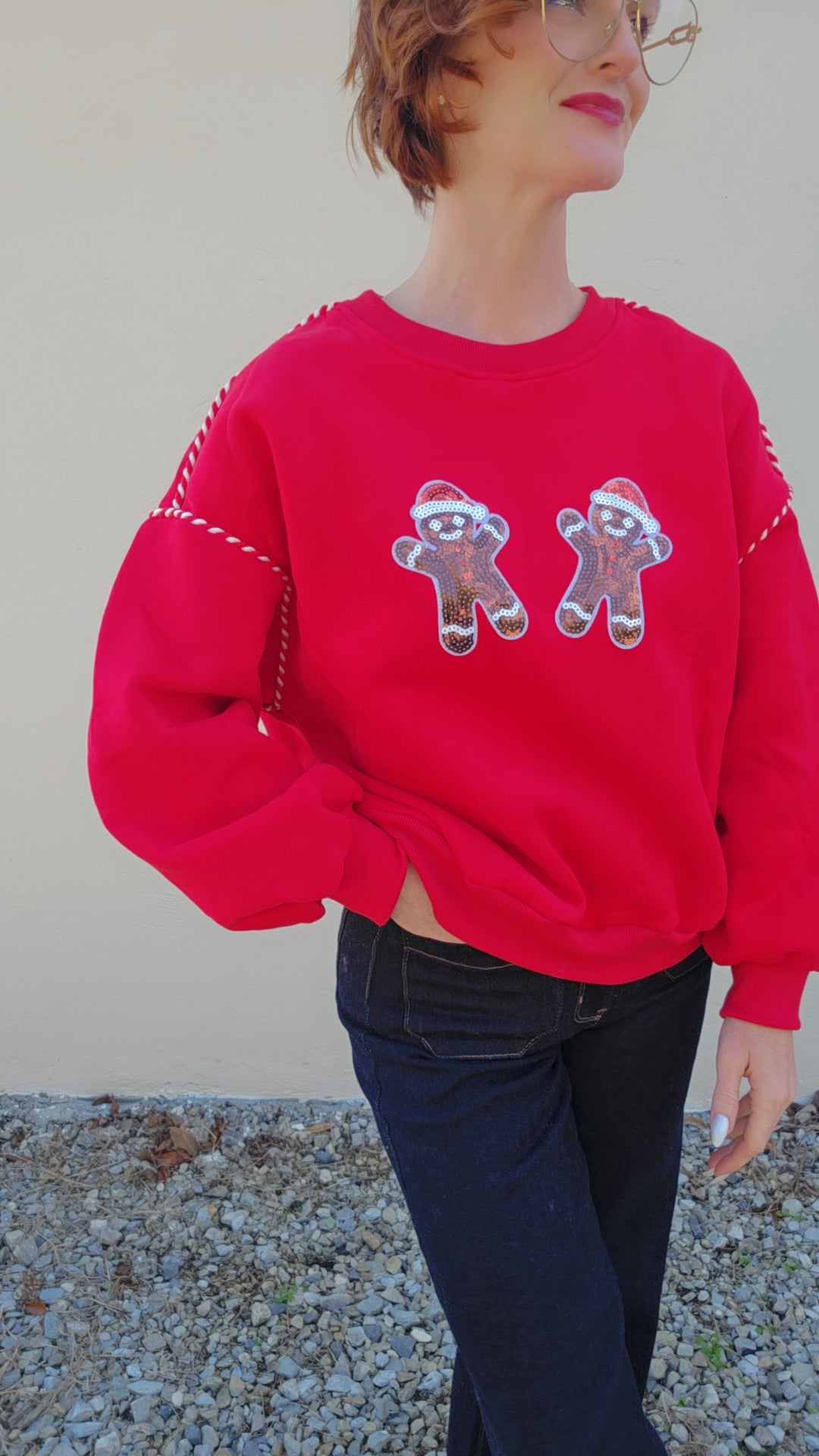 Person wearing a red sweater with gingerbread man designs against a neutral background