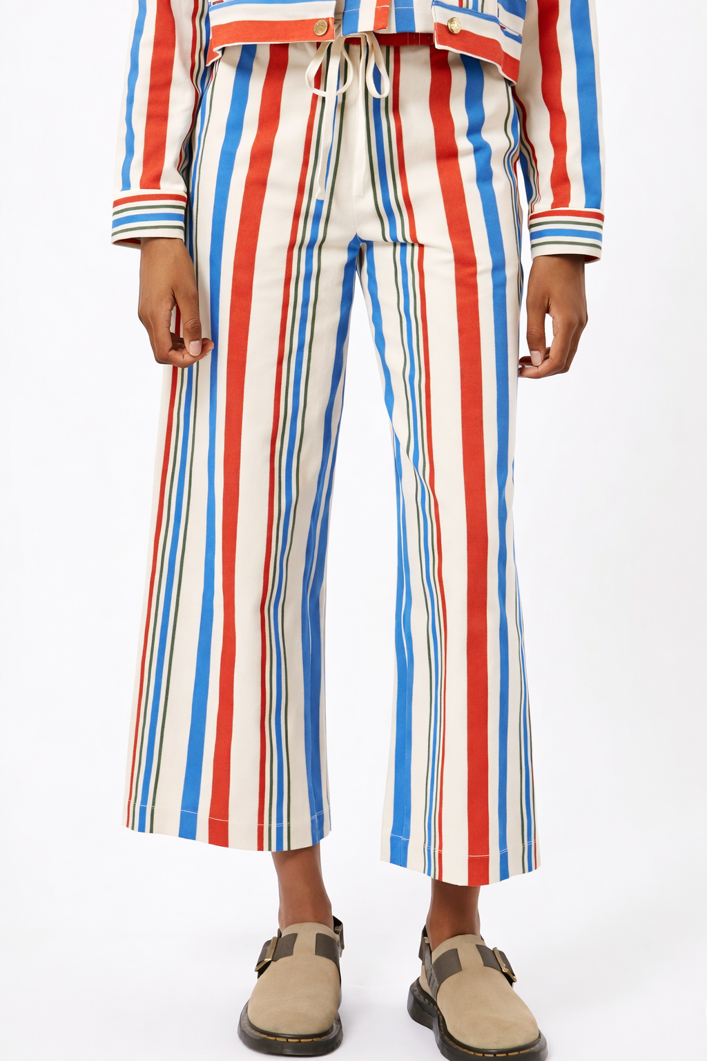 Person wearing a colorful striped outfit with wide-leg pants on a white background
