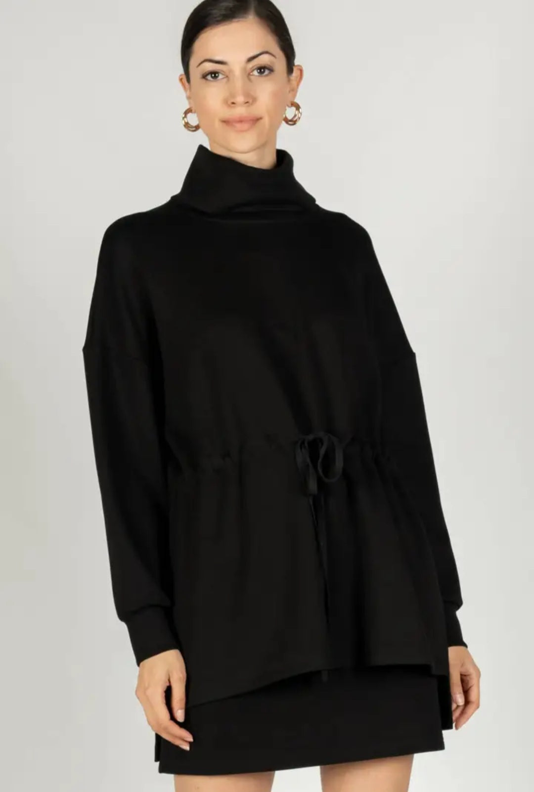 Woman wearing a black poncho against a white background