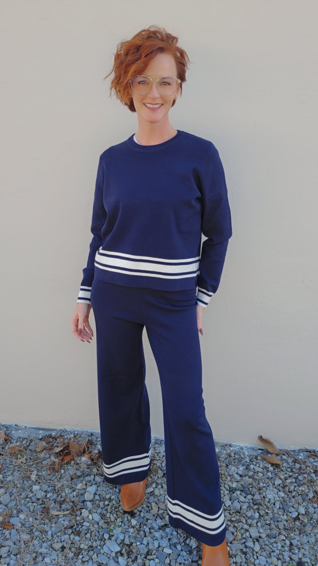Woman wearing a blue outfit with white stripes standing on a textured surface.