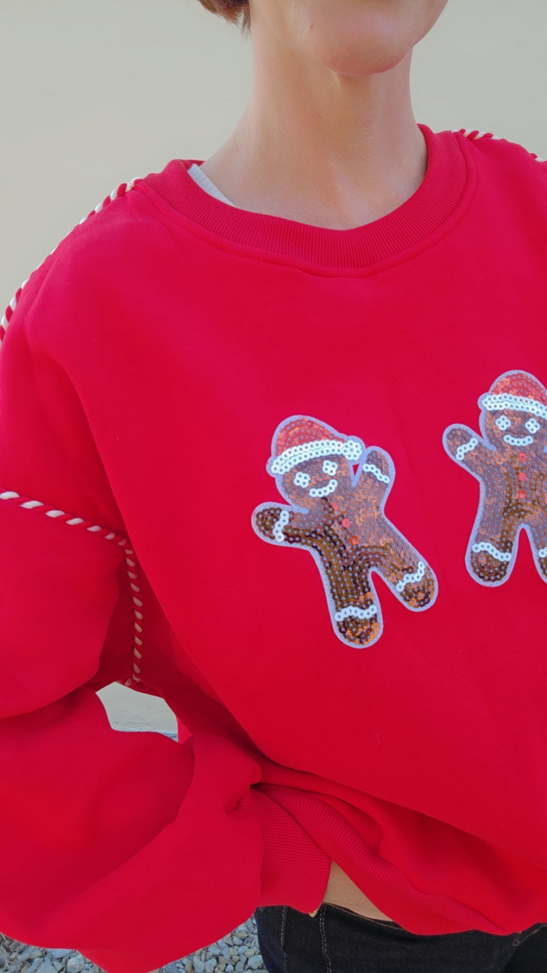 Red sweatshirt with gingerbread man designs worn by a person.