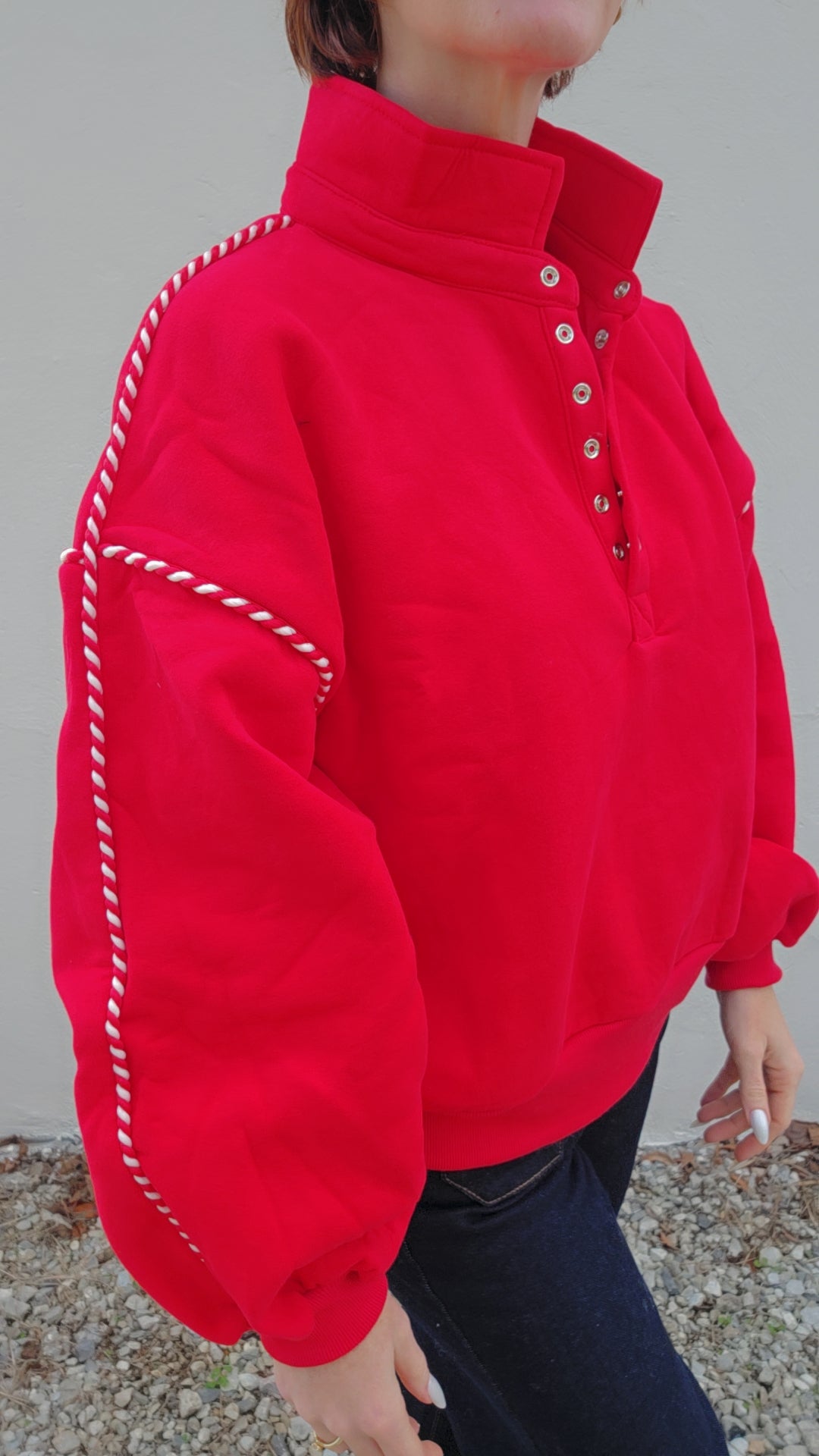 Red fleece jacket with white stitching on a neutral background