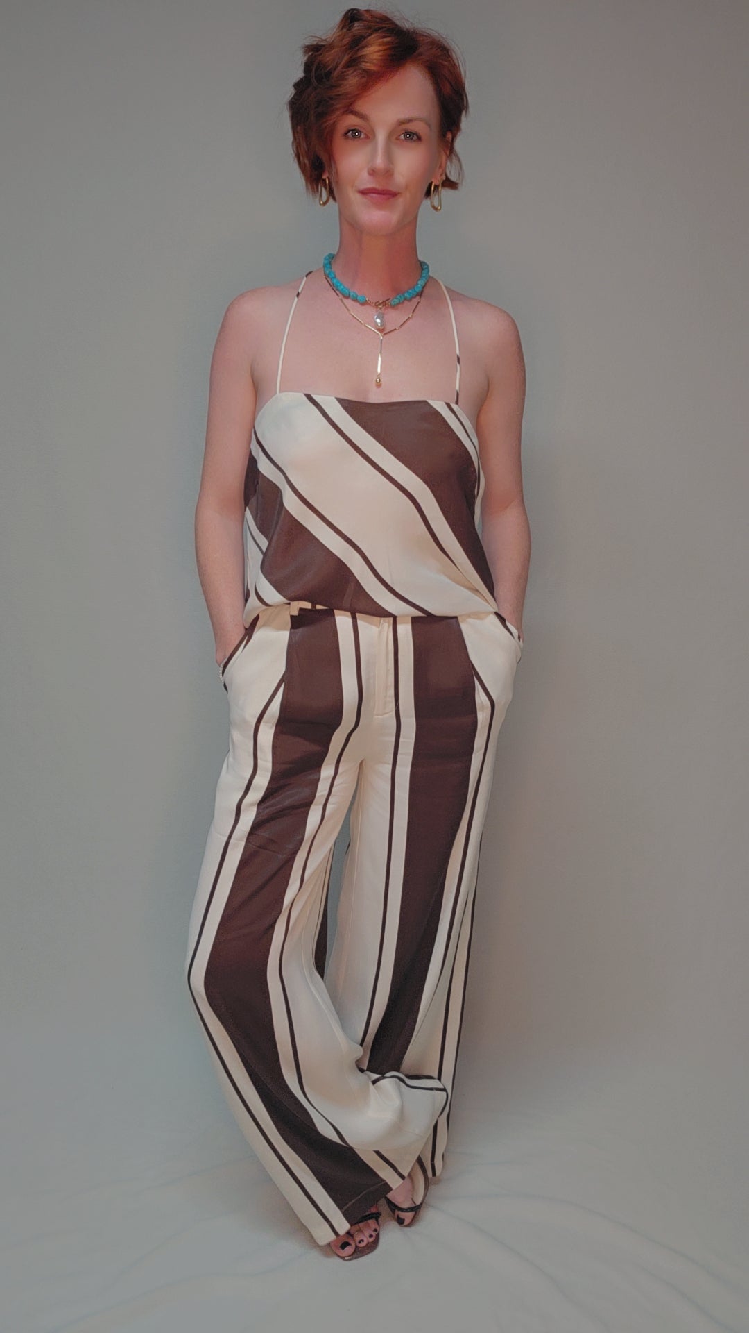 Woman wearing a brown and beige striped jumpsuit against a plain background