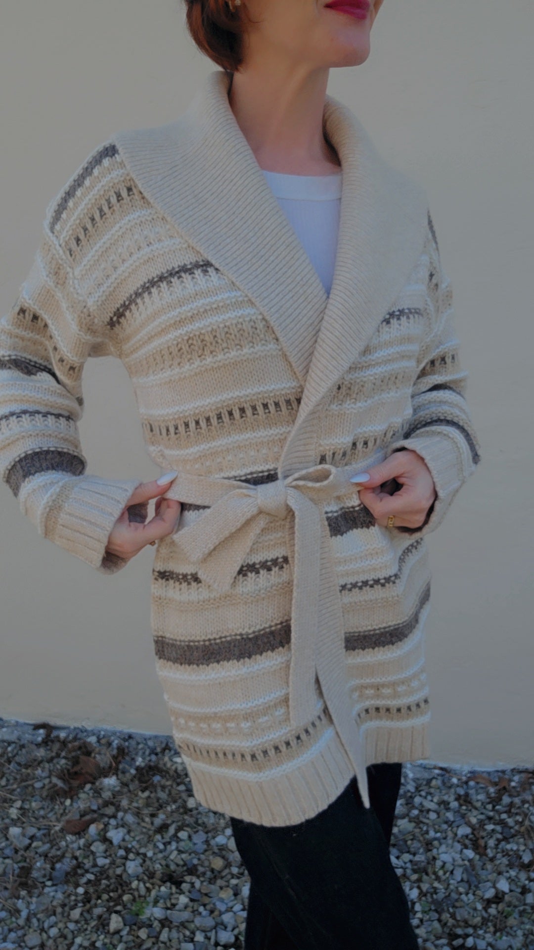 Person wearing a patterned cardigan with a plain background