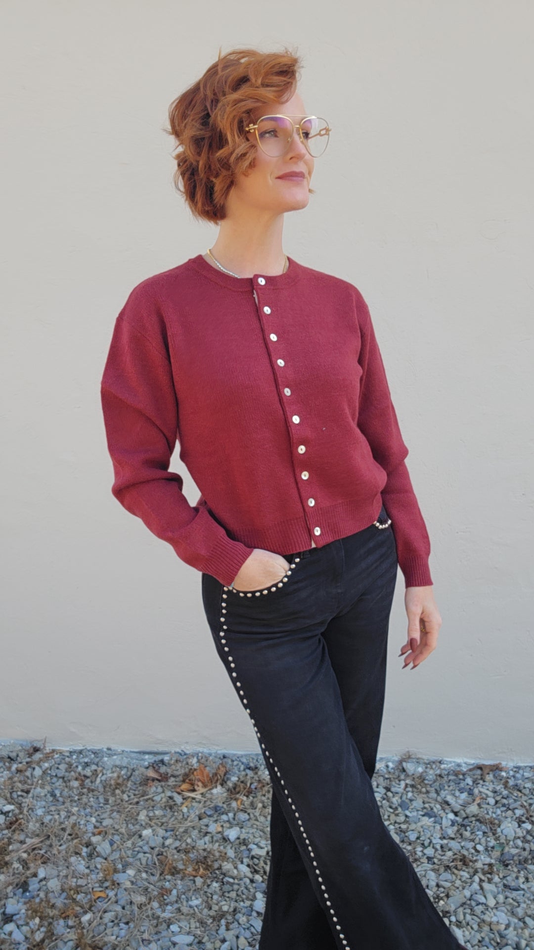 Woman wearing a red cardigan with white buttons against a plain background