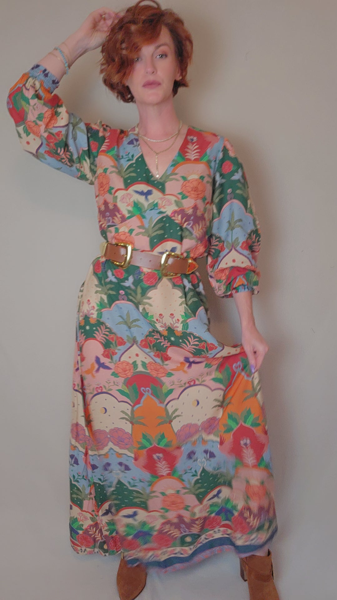 Woman wearing a colorful floral dress against a plain background