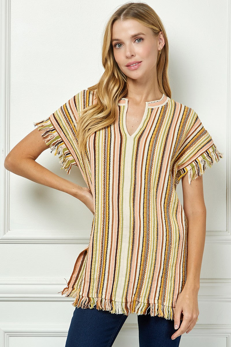Woman wearing a striped, short-sleeve top against a white wall.